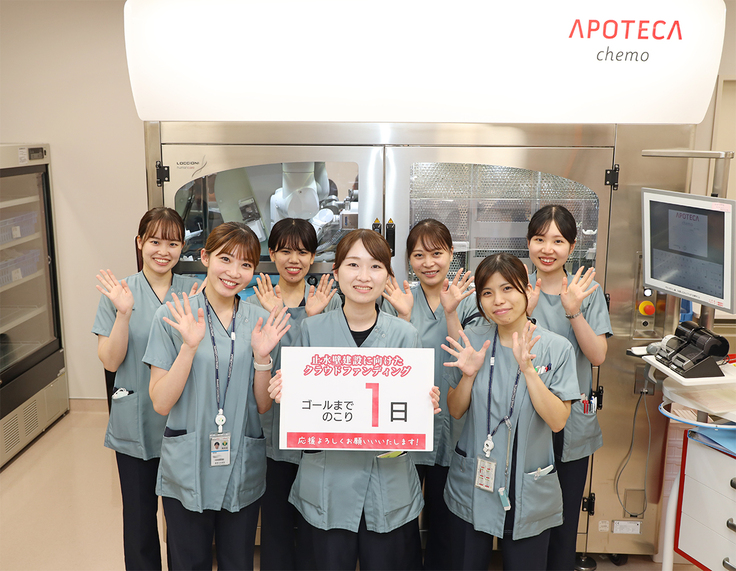 調剤室内　抗がん剤自動調製装置（APOTECA）の前にて