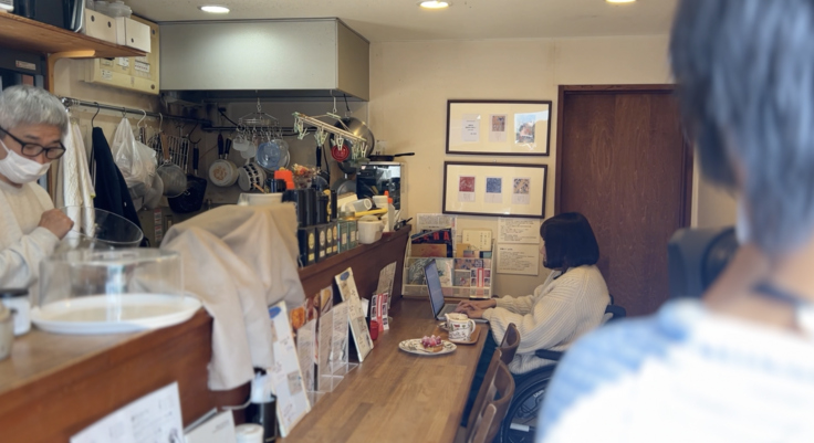 理事長豆塚エリがコージーコーナーにてカウンターに座って執筆作業をしている様子