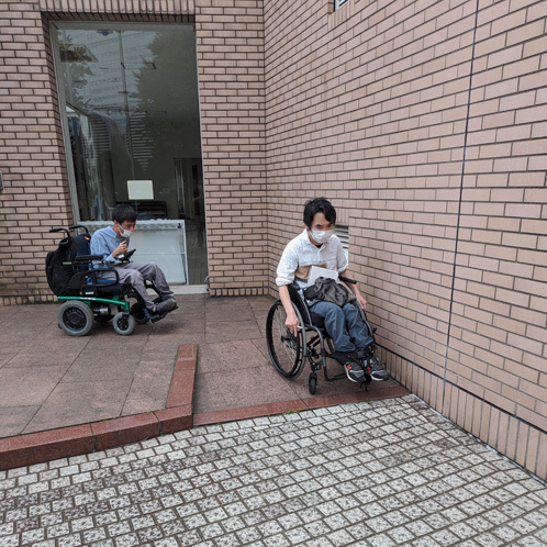 施設入口のスロープを下ろうとしている岩切と小野