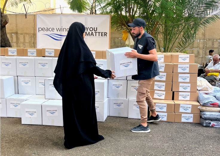 箱詰めした支援物資を受け取る避難者