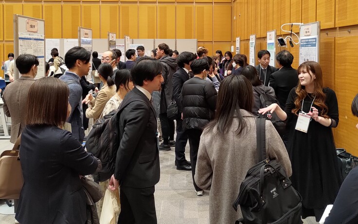 実践発表の様子。会場にポスターが掲示されており、その前で発表者が説明を行っている。