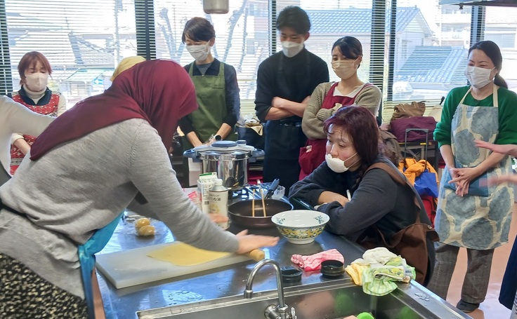 揚げ菓子のたねを伸ばす講師（左）の手元を見つめる参加者＝千葉市・幕張公民館で2025年2月8日