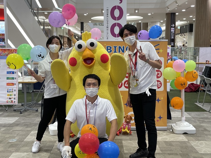 ドコモのイベントでドコモのキャラクターマスコットと代表深谷、他スタッフ2名が風船を持って楽しそうに呼び込みをしている写真。