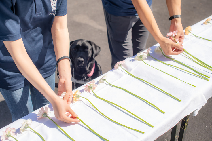 献花の様子。慰霊碑の前に置かれたテーブルの上に白い布が敷かれており、その上にガーベラの花を１輪ずつ献花する職員。